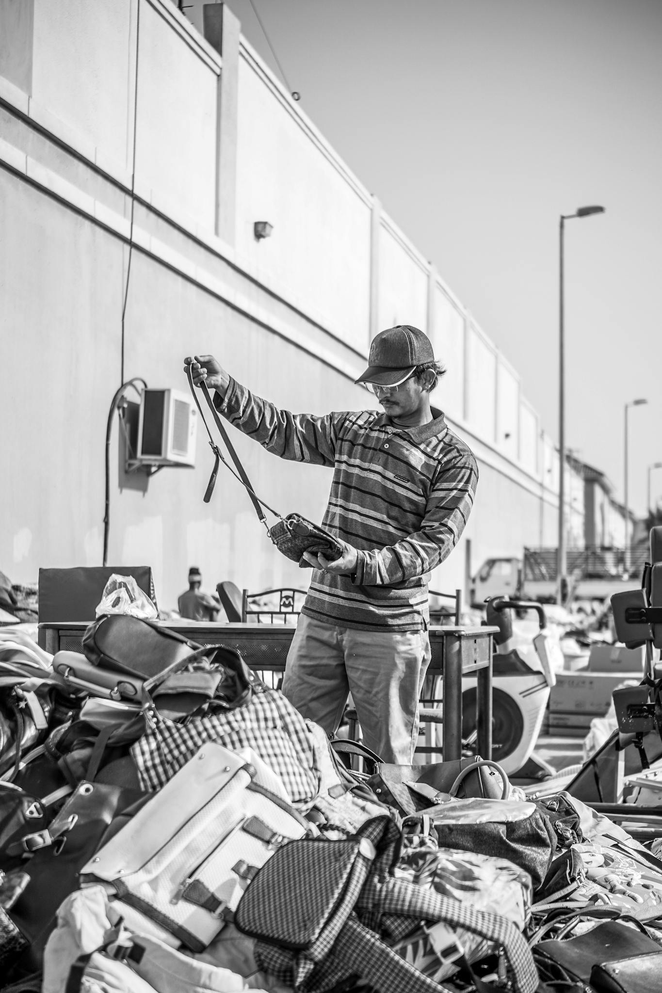 A man examines goods at an outdoor garage sale, searching through piles.